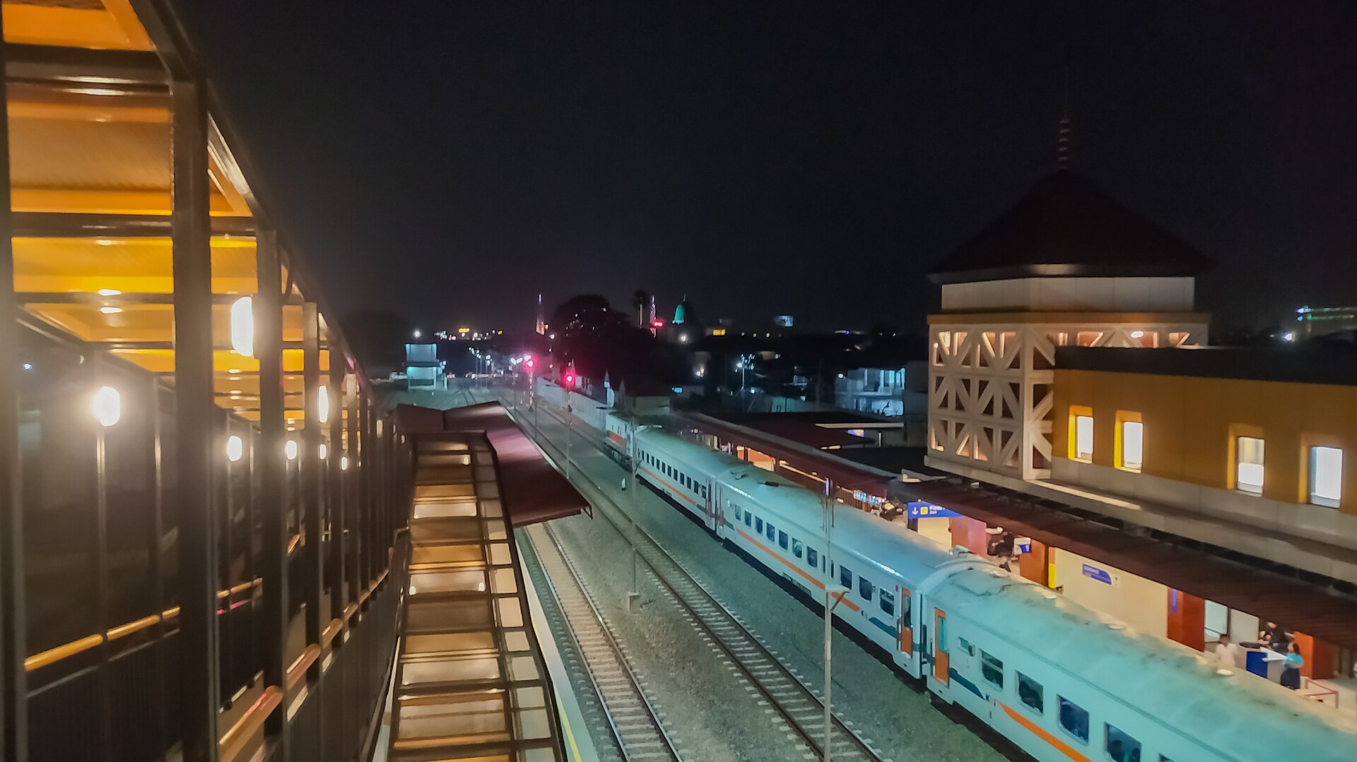 A commuter train waiting under the lights of Gedebage Station at night